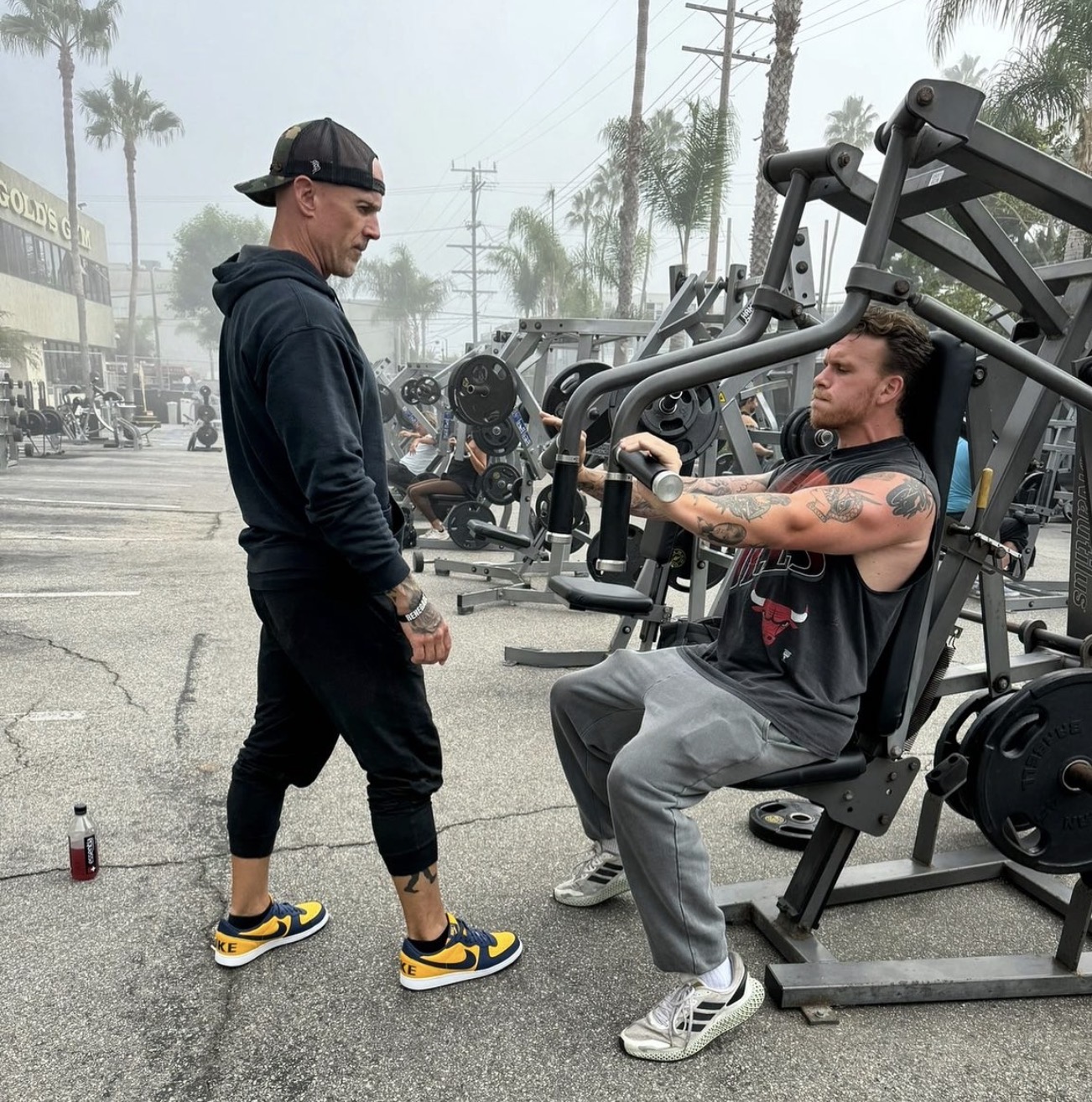 Nick Blauer coaching a client through a machine press in an outdoor gym